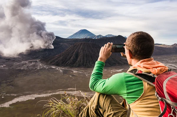 L'homme est assis sur la colline et fait une photo sur son smartphone Photos De Stock Libres De Droits