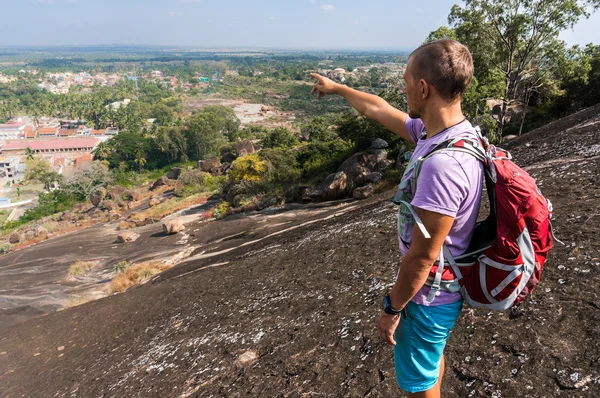 Joven está parado en una montaña y mostrando algo — Foto de Stock