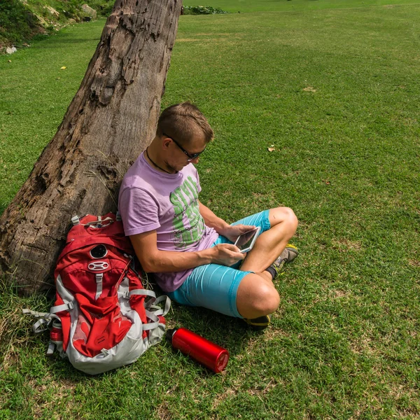 Homme assis sous l'arbre et utilisant sa tablette — Photo