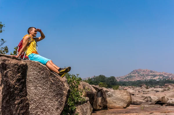 Jeune homme assis sur la pierre et profitant de la vue après la randonnée — Photo