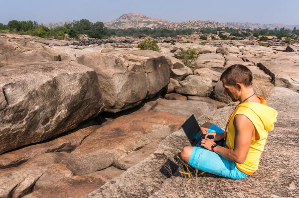 Junger Mann sitzt auf dem Berg mit schöner Aussicht und arbeitet mit Laptop — Stockfoto