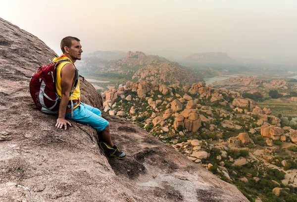 Jeune homme assis sur la montagne et profitant de la vue après la randonnée — Photo