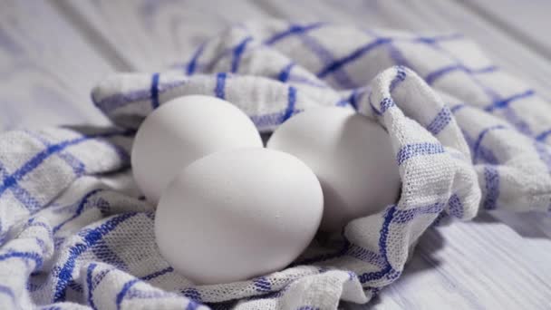 Tres huevos de pollo crudos en la mesa, tiro giratorio, huevos crudos frescos blancos de pollo en un trozo de tela — Vídeos de Stock