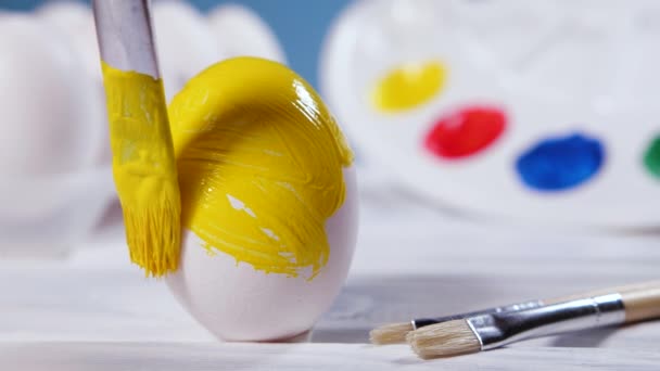 Живопис великодніх яєць з жовтим пензлем, підготовка до весняних свят, релігійне святкування, художнє барвисте уявлення — стокове відео
