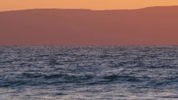 Paisaje marino dramático natural del amanecer con las montañas, sol del atardecer que brilla a través de las ondas, océano y mar cámara lenta 4k — Vídeo de stock