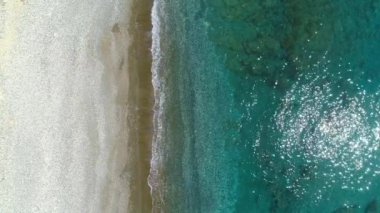 Hava manzarası, deniz ya da okyanus üzerinde güneşli bir gün. Tatil ve tenha bir yerde rahatlamak. Yaz günü deniz manzarası. Akdeniz plajı. Temiz su dokusu. Üst görünüm 4K