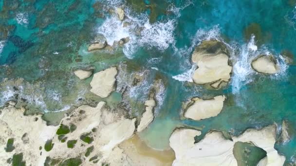 Luftaufnahme von Wellen brechen an Felsen in einem blauen Ozean. Meereswellen am schönen Strand aus der Vogelperspektive Drohne 4k erschossen. Vogelperspektive auf Meereswellen, die von oben gegen eine leere Steinklippe krachen. — Stockvideo