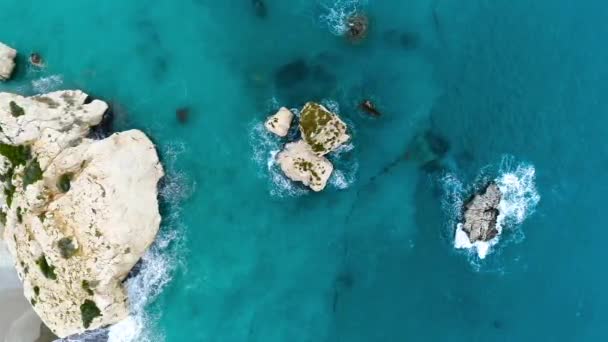 Luftaufnahme von Wellen brechen an Felsen in einem blauen Ozean. Meereswellen am schönen Strand, Drohne aus der Luft 4k erschossen. Vogelperspektive auf Meereswellen, die von oben gegen eine leere Steinklippe krachen — Stockvideo