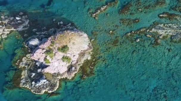 青い海の島と浅い水。石からの鋭い崖。ターコイズブルーの水と岩のサンゴ礁、美しいビーチの空中ビュードローンでの海の波4kショット、観光地、休暇の場所、キプロス — ストック動画
