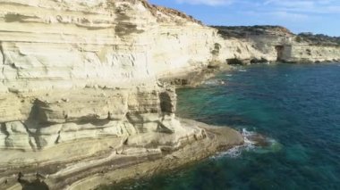 Deniz kıyısının havadan görünen manzarası, dağlı deniz, dik kayalık uçurum, güzel turistik manzara. Turkuaz okyanus insansız hava aracı atışının kıyısındaki beyaz kayalıklar. Su dalgaları kayalara çarpıyor.