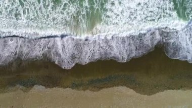 Mavi enerjinin ve berrak okyanus suyunun canlılığı. Yukarıdan aşağıya insansız hava aracı perspektifinde güçlü fırtınalı deniz dalgaları. Akdeniz 'de köpüklü beyaz dokusuyla çarpışan dalga hattı