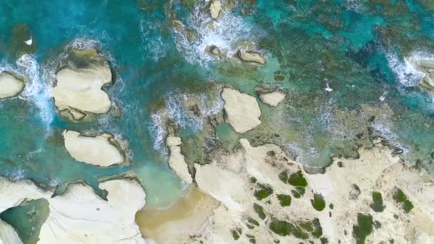 Górny widok fal rozbija się na skałach w błękitnym oceanie. Fale morskie na pięknej plaży widok z powietrza dron 4k strzał. — Wideo stockowe