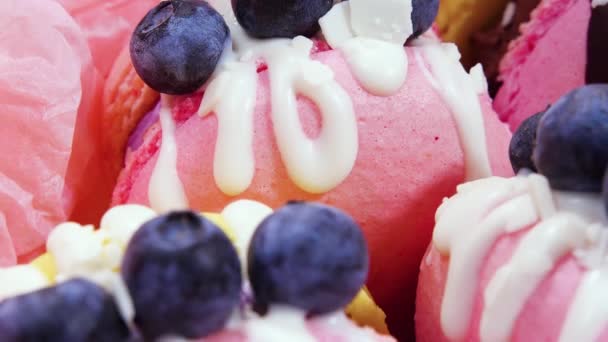 Handgemachte schöne Makronen, Süßspeisen, Dessert mit frischen Erdbeeren und Blaubeeren dekoriert mit Schokolade, zarte gelbe und rosa Kuchen, Zucker und gesunde Lebensmittel — Stockvideo