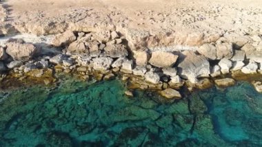 Okyanus mavisi su ve kayaların insansız hava aracı görüntüsü sakin bir deniz kayalık dağı, dünyanın ve mavi denizin kıyısını, dramatik jeolojik harikayı, güzel manzarayı yıkar.