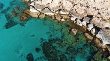 Deniz kıyısındaki kayalık uçurum, okyanus mavi su ve kayaların insansız hava aracı tarafından 4k görüntüsü, Dünyanın Kıyısı ve mavi deniz plajı, dramatik jeolojik merak, güzel manzara.