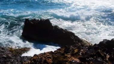 Deniz fırtınası, yıkıcı ve muhteşem, okyanus dalgaları kıyıdaki kayalara çarpıyor ve bir su patlaması yaratıyor.