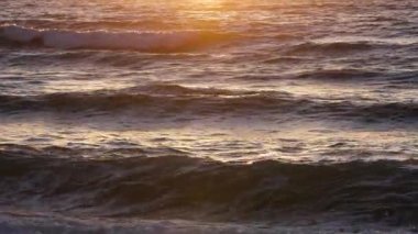 Sunset 'te fırtınalı deniz, doğal dramatik deniz manzarası. Gün batımı ya da gündoğumu güneşi altın dalgalar, okyanus ve deniz boyunca parıldıyor ağır çekim 4k