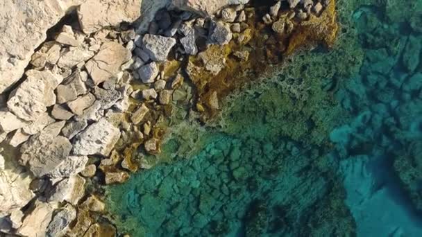 Okyanus mavisi su ve kayaların insansız hava aracı görüntüsü sakin bir deniz kayalık dağı, dünyanın ve mavi denizin kıyısını, dramatik jeolojik harikayı, güzel manzarayı yıkar. — Stok video