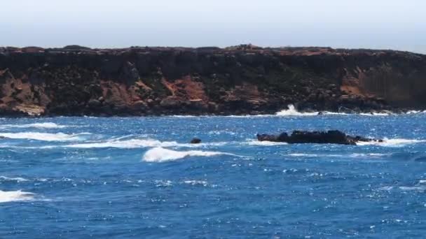 Tempestade marítima, imagens de paisagens 4k de águas e rochas azuis oceânicas, paisagens ensolaradas diurnas, Devastantes e espetaculares, ondas oceânicas colidem nas rochas da costa criando uma explosão de água — Vídeo de Stock