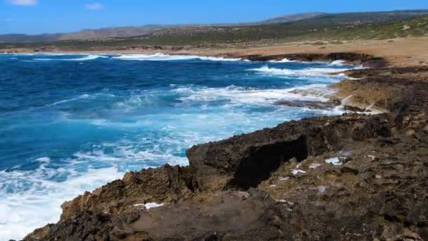 海の嵐、青い海と岩の4kの風景映像、晴れた昼間の風景、海岸の岩の上に破壊的で壮大な海の波がクラッシュし、水の爆発を作り出します — ストック動画