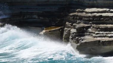 Deniz fırtınası konsepti, okyanus mavi su ve kayaların manzara görüntüleri, güneşli gündüz deniz manzarası, yıkıcı ve muhteşem, okyanus dalgaları kıyıdaki kayalara çarpıyor ve bir su patlaması yaratıyor.