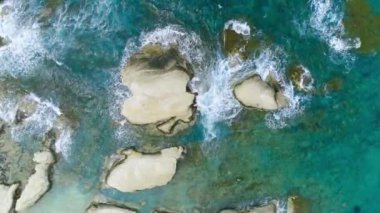 Güzel kayalık deniz kıyıları, Turkuaz okyanus dalgaları kayalık bir dağın yüksek uçurumunda kırılıyor. Kumsalda tehlikeli deniz dalgaları. Hava Aracı 4k