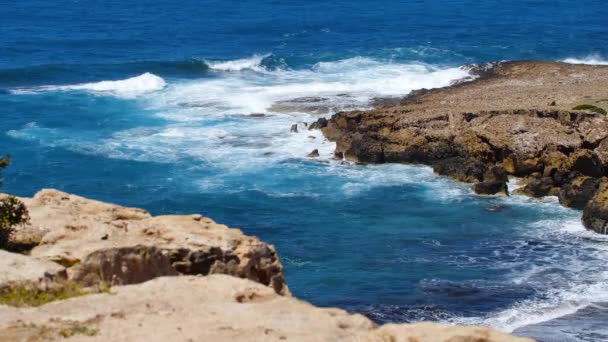 Havsblått vatten och klippor, Soliga dagtid kustlandskap, Förödande och spektakulära, havsvågor krascha på klipporna vid kusten skapar en explosion av vatten — Stockvideo