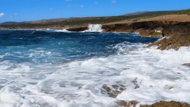 Agua azul marino y rocas, Soleado paisaje marino diurno, Devastador y espectacular, las olas oceánicas chocan contra las rocas de la costa creando una explosión de agua — Vídeos de Stock