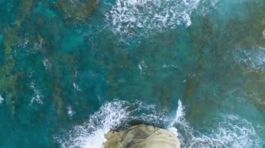 Kıbrıs 'ta büyüleyici kayalık bir plaj, jeolojik bir mucize, deniz dalgaları sahile taşlarla vuruyor. Güzel Arkaplan, Denizde Kayalıklar, 4k Üst Hava Manzarası