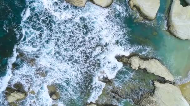 Encantadora playa escarpada en Chipre, una maravilla geológica, las olas del mar chapotean contra la playa con rocas. Hermoso fondo, Acantilados en el mar, 4k Vista aérea superior — Vídeos de Stock