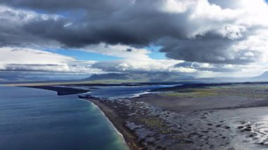 İzlanda 'da benzersiz siyah kumlu sahil. Yeşil küçük tepeleri olan eşsiz kıyı şeridi. 4k' lik olağanüstü soyut manzarası var.