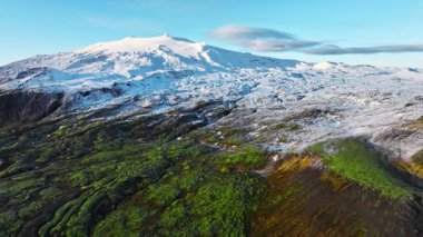 İzlanda 'daki dağlık arazi, baharın başlarında yeşil yosun ve karla kaplı dağ, nefes kesen hava manzarası, karlı manzaralarda macera. Yüksek kalite 4k görüntü