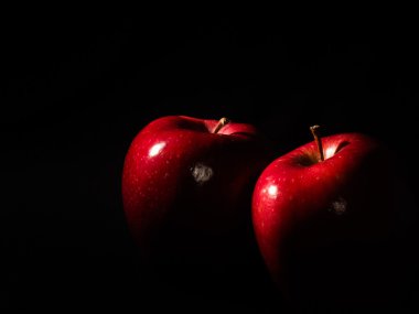 Siyah arka plan üzerine iki kırmızı elma