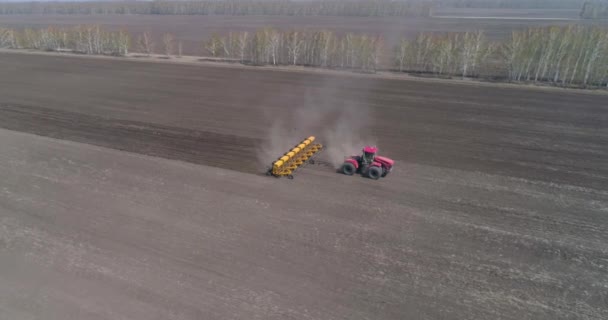 Výsev. Farmář na velkém traktoru zasévá úrodu. — Stock video