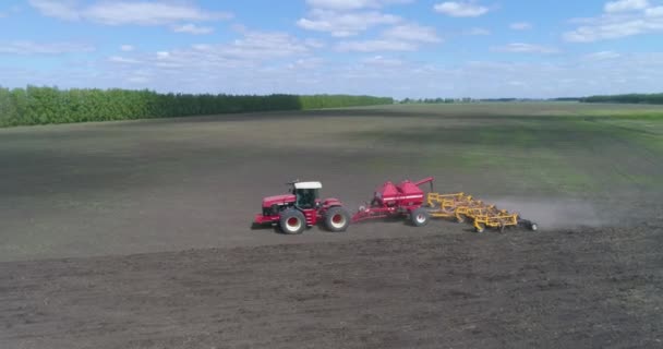 Um agricultor em um trator semeia e arado o solo ao mesmo tempo. — Vídeo de Stock
