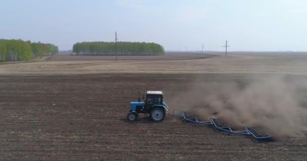 Sowing preparation. A farmer on a tractor cultivates the soil in the field. — Stock Video