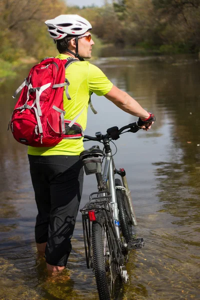 Cyklista prochází řeka. — Stock fotografie