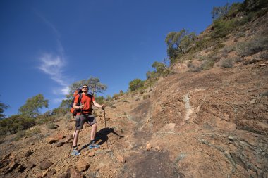 Güneşli bir günde dağlarda hiking bir sırt çantası olan bir adam.
