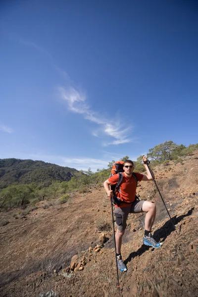 Güneşli bir günde dağlarda hiking bir sırt çantası olan bir adam.
