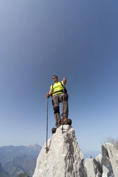 Een man met een rugzak wandelen in de bergen op een zonnige dag. — Stockfoto