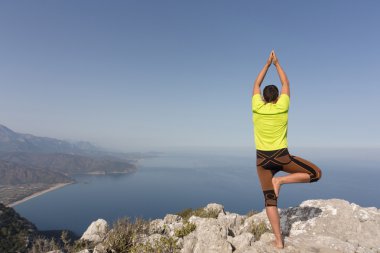 Güneşli bir dağın tepesinde genç adam.