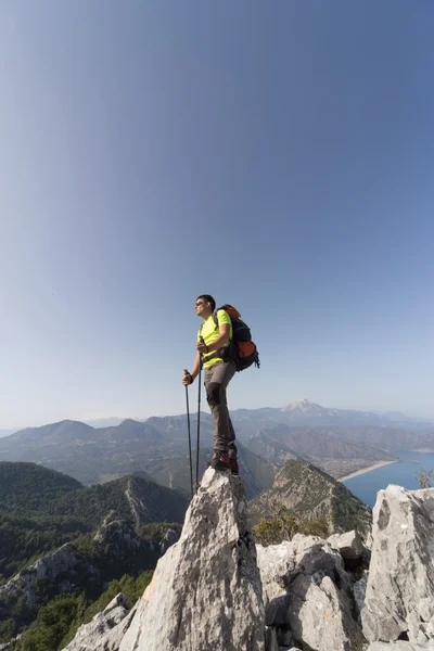 Νεαρός με σακίδιο στην κορυφή του βουνού μια ηλιόλουστη μέρα. — Φωτογραφία Αρχείου