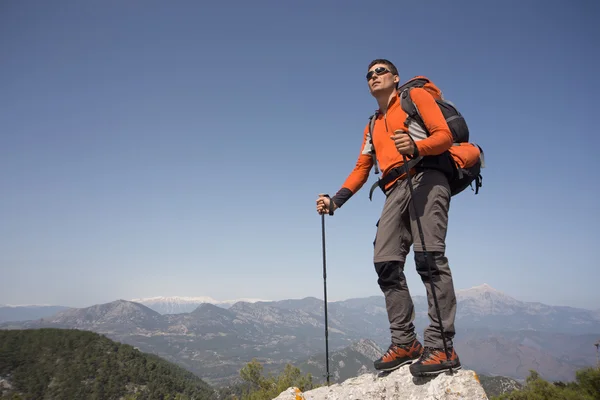 Junger Mann mit Rucksack auf einem Berggipfel an einem sonnigen Tag. — Stockfoto