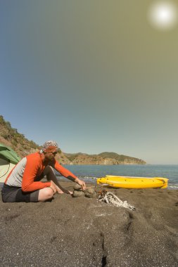 Adam kayak ve güneşli bir çadır ile sahilde.