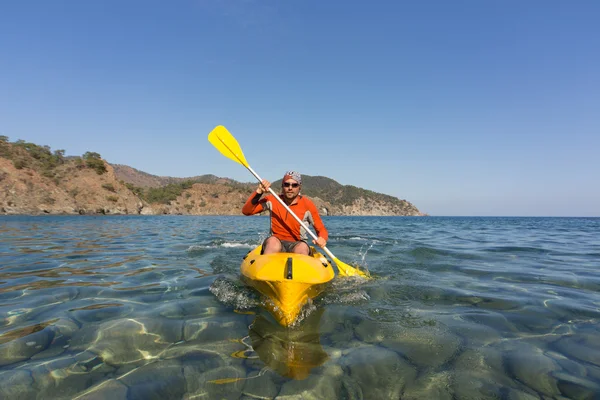 Um homem viajando de canoa ao longo da costa no verão . — Fotografia de Stock