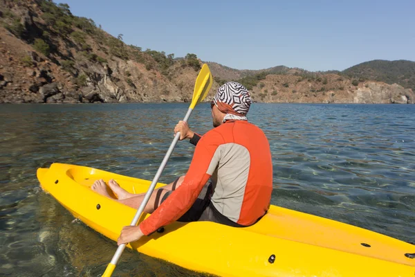 Un uomo che viaggia in canoa lungo la costa in estate . — Foto Stock