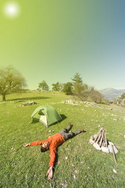 Man camping with a tent in the mountains in the summer on a sunny day.