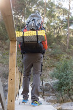 Genç adam bir sırt çantası ile bir dağ nehir taşımak için.