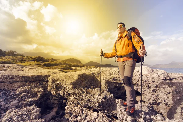 Ung man med ryggsäck på en bergstopp på en solig dag. — Stockfoto