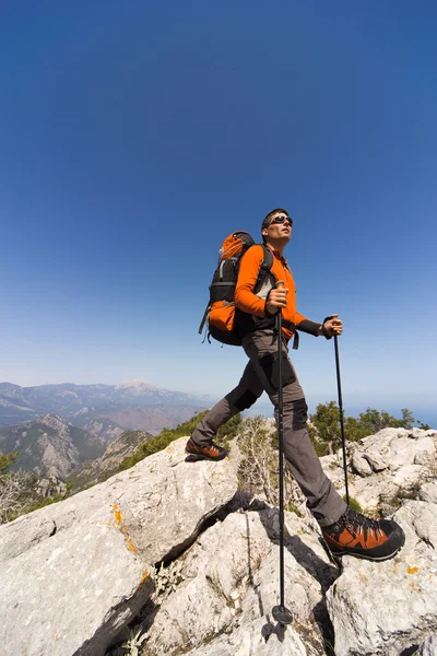 Ung man med ryggsäck på en bergstopp på en solig dag. — Stockfoto